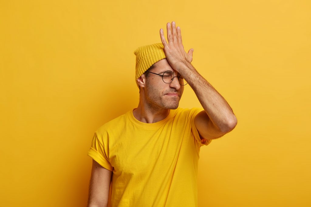 kognitive Störung typ in gelbem Shirt fasst sich an den Kopf